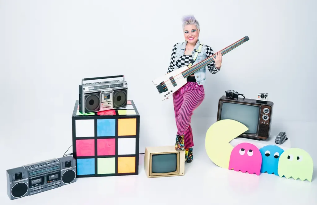 melanie deloreans holding a bass surrounded by 80s props