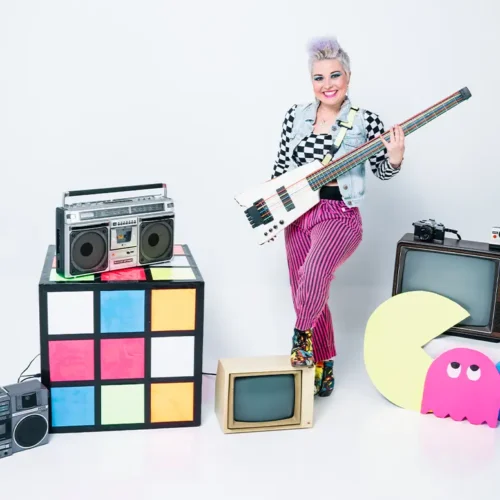 melanie deloreans holding a bass surrounded by 80s props