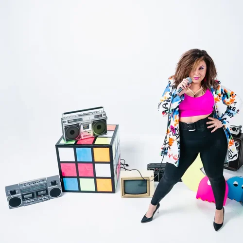 rianna delorans holding a microphone surrounded by 80s props